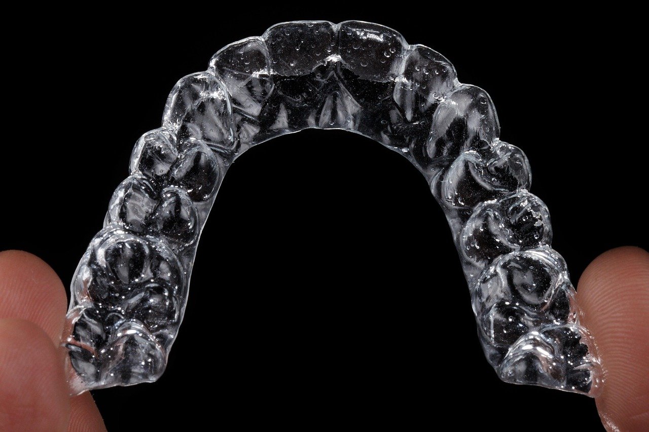 Ortodoncia invisible: tipos, precios, proceso y resultados reales Sonrisa de persona mostrando alineadores transparentes para ortodoncia invisible.