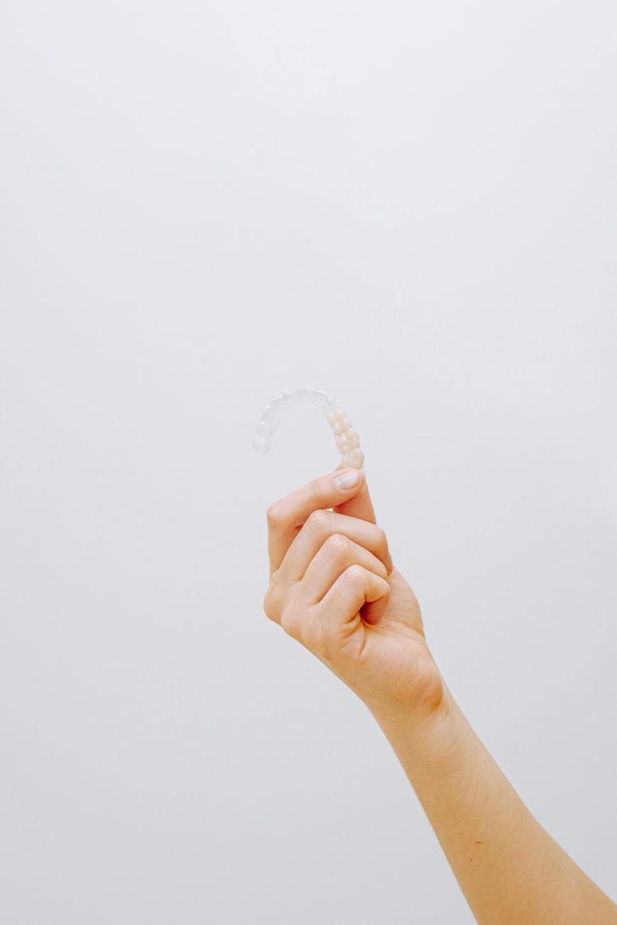 Ortodoncia invisible: tipos, precios, proceso y resultados reales Persona mostrando alineadores transparentes invisibles para ortodoncia sin brackets.